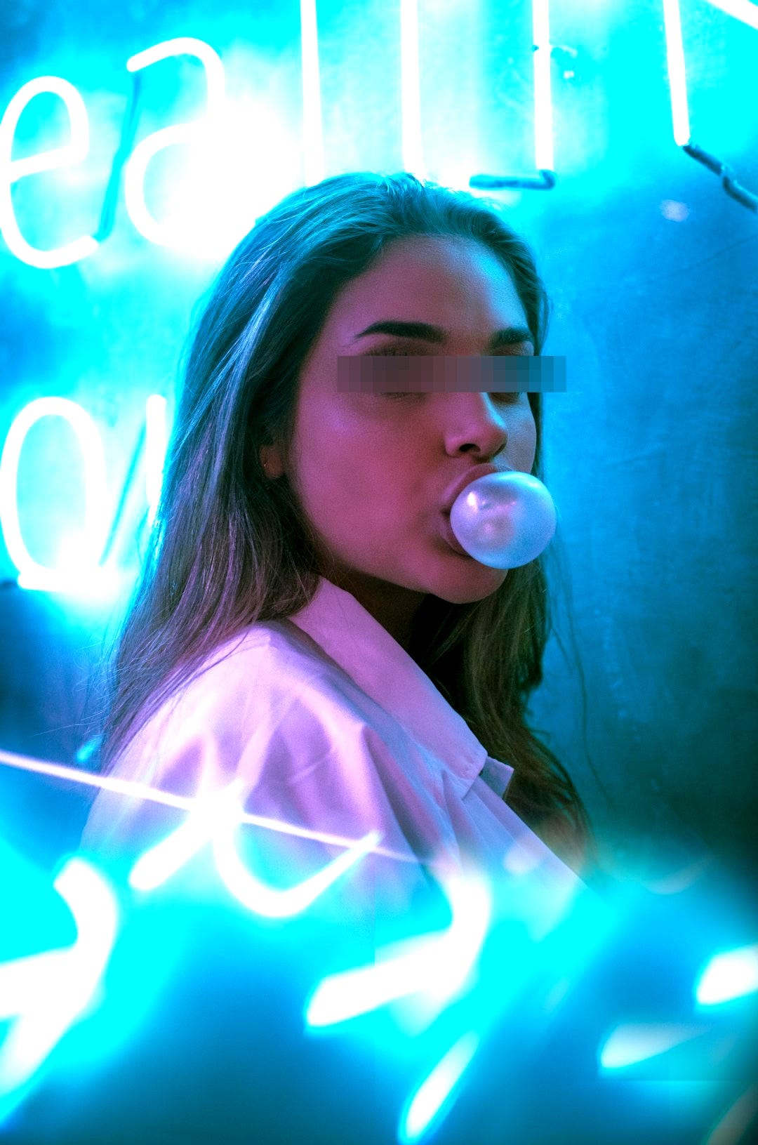 selective focus photo of woman blowing gum standing in front of turned-on neon signage selective focus photo of woman blowing gum standing in front of turned-on neon signage