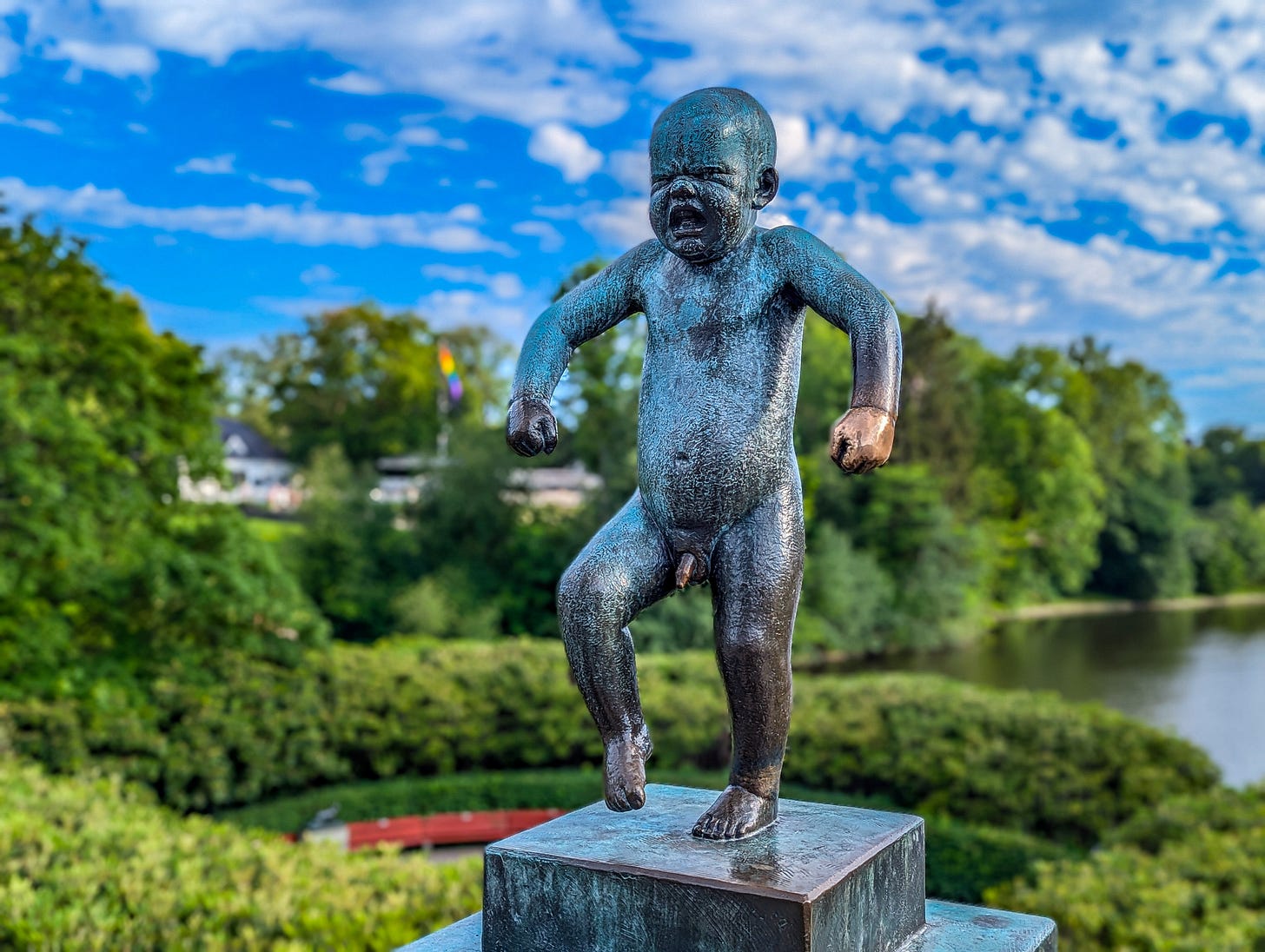 Bronze sculpture of Angry Baby with the park in the background.