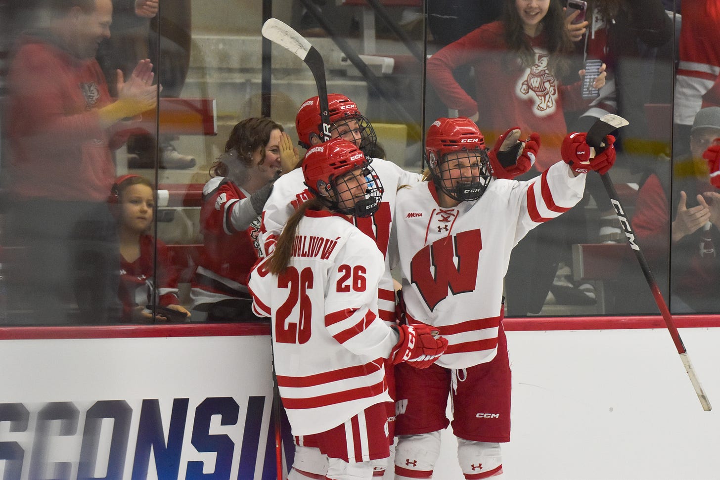 wisconsin women's hockey players huddling and hugging on the glass of the rink wisconsin women's hockey players huddling and hugging on the glass of the rink
