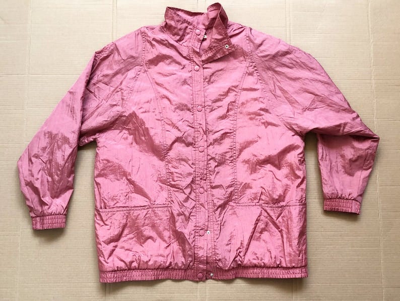 May include: A pink nylon jacket with a snap closure, two pockets, and a ribbed hem and cuffs.