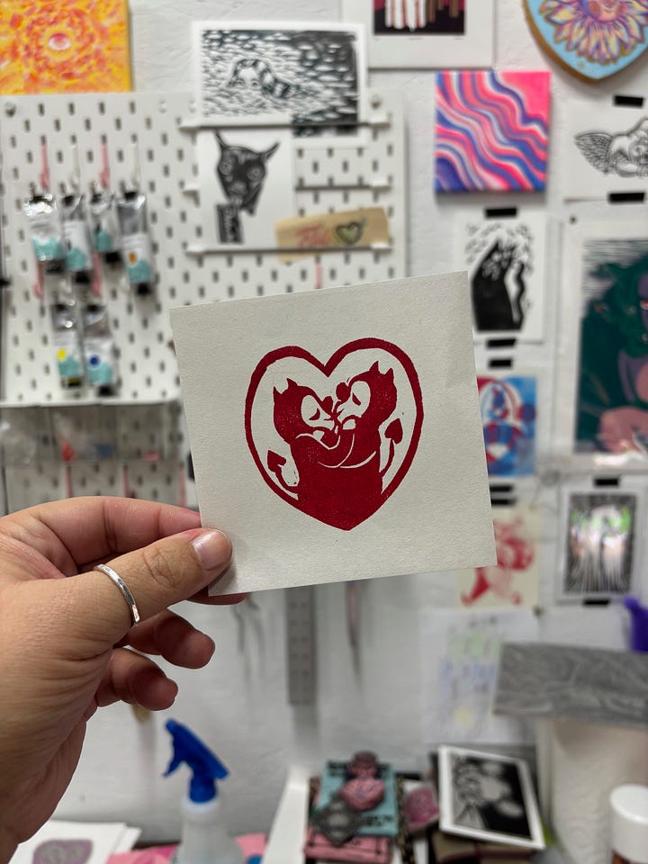 one valentine is a clown face in a heart and the other is two little demon guys smooching inside a heart