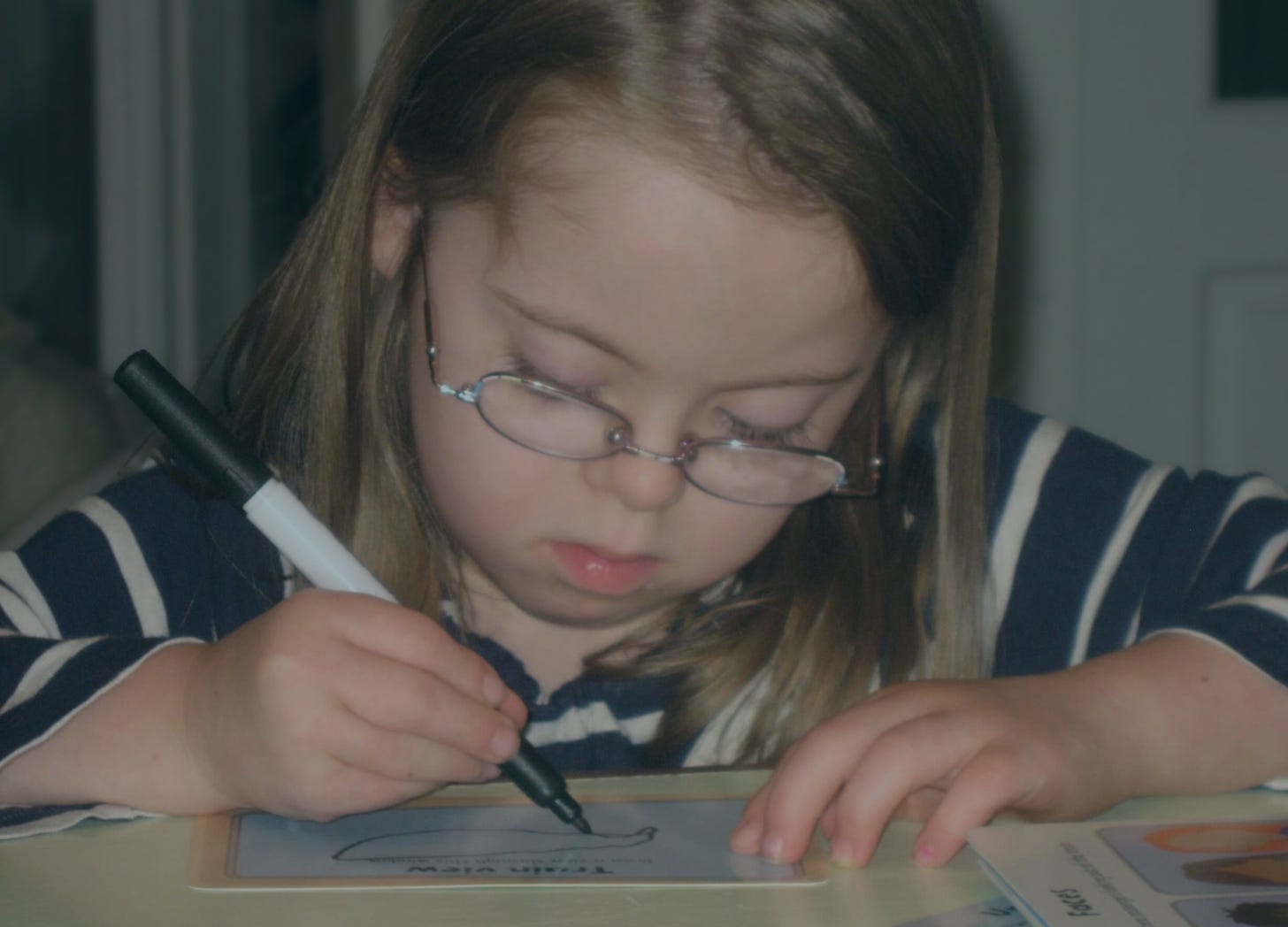 Penny sits at a desk writing on a paper