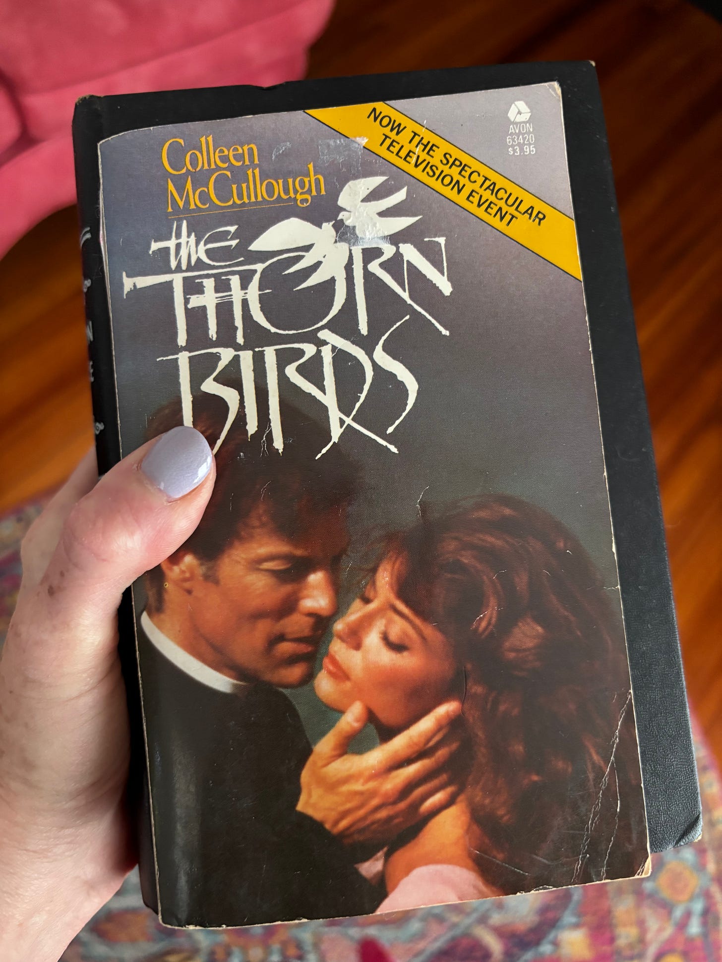 writer holding a copy of The Thorn Birds which shows an image of Meggie and Father Ralph on the cover writer holding a copy of The Thorn Birds which shows an image of Meggie and Father Ralph on the cover