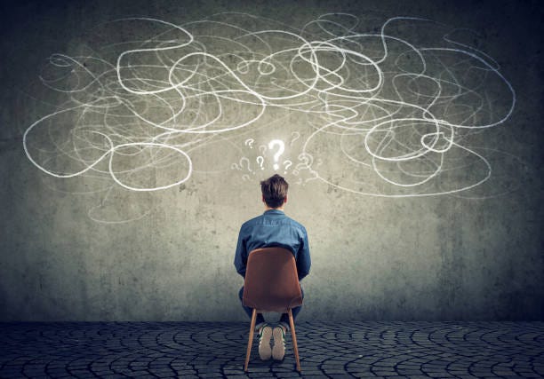 businessman sitting on chair looking at a scribble on a wall feeling confused Back view of a thoughtful young businessman sitting on chair looking at a scribble on a wall feeling confused with too many questions stressed businessman stock pictures, royalty-free photos & images
