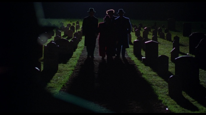 Silhouettes of three gangsters walking through a dimly lit cemetery at night, their shadows stretching between headstones—stylized and moody.