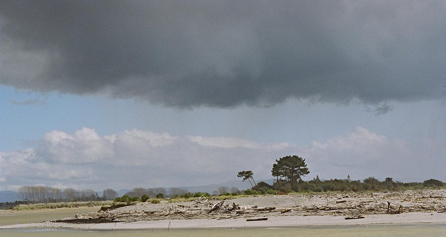 Image is of a beach at low tide with a large, dark cloud hanging above, indicating an impending storm. Image is of a beach at low tide with a large, dark cloud hanging above, indicating an impending storm.
