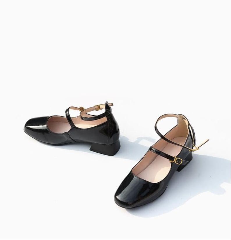May include: Two pairs of black patent leather ankle strap heeled shoes with gold buckles.