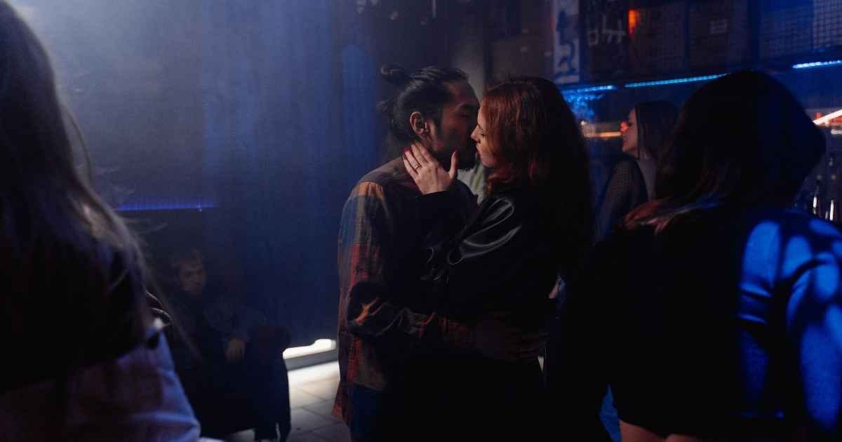 Man and woman kissing in a lively nightclub with colorful lighting Man and woman kissing in a lively nightclub with colorful lighting