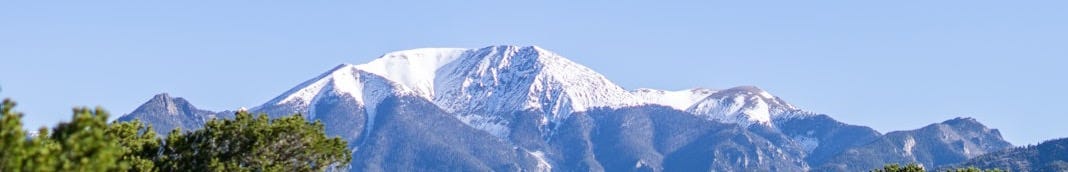 a view of a mountain range with trees in the foreground
