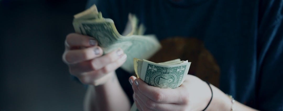 focus photography of person counting dollar banknotes focus photography of person counting dollar banknotes