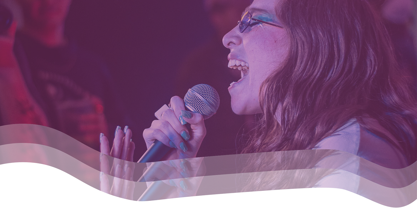 A woman holds a microphone and sings.