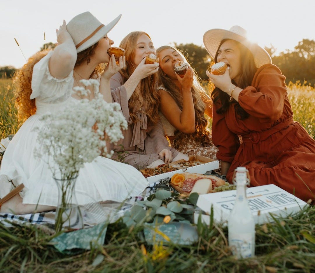 a group of women sitting on top of a grass covered field
