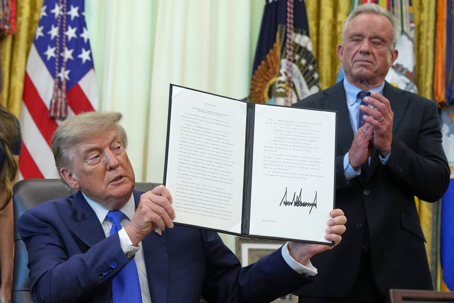 President Trump holds up the signed executive order in the Oval Office as RFK Jr. applauds behind him. President Trump holds up the signed executive order in the Oval Office as RFK Jr. applauds behind him.