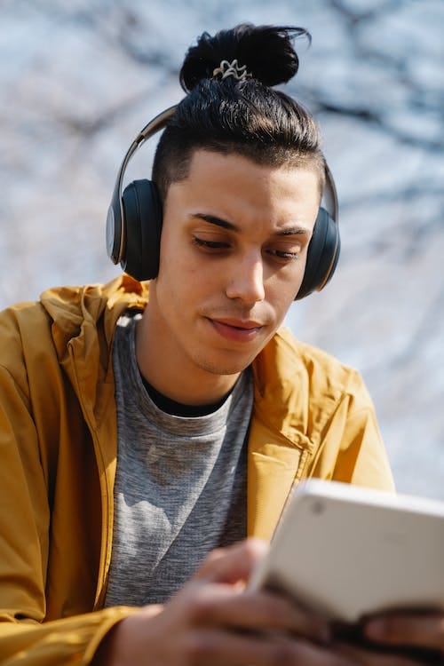 Free Ethnic man in headphones with smartphone on street Stock Photo