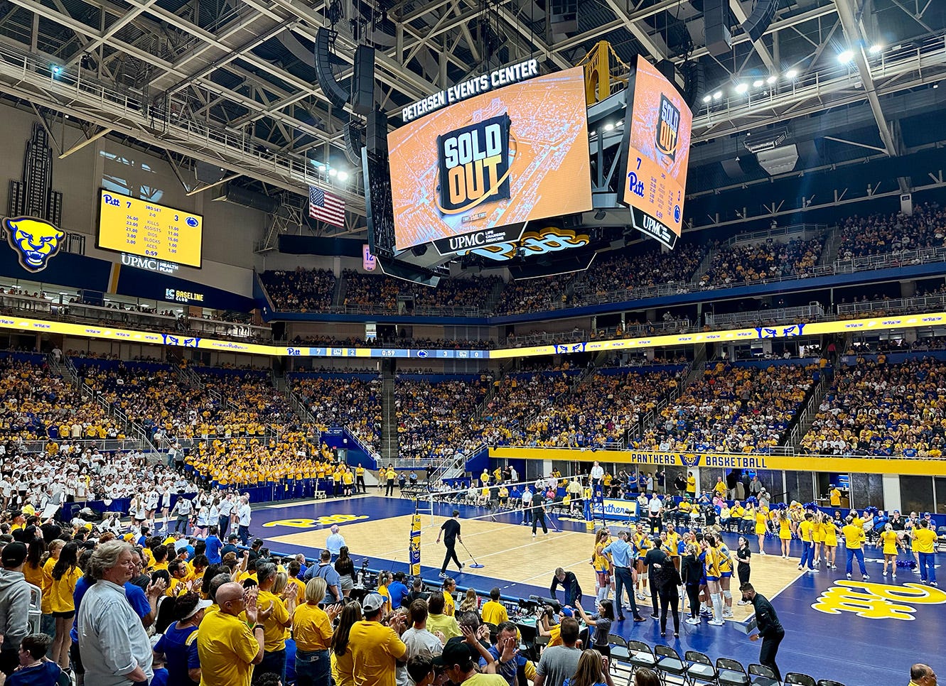 Photo shows a full Petersen Events Center for Pitt Volleyball's match versus Penn State. The scoreboard reads SOLD OUT.
