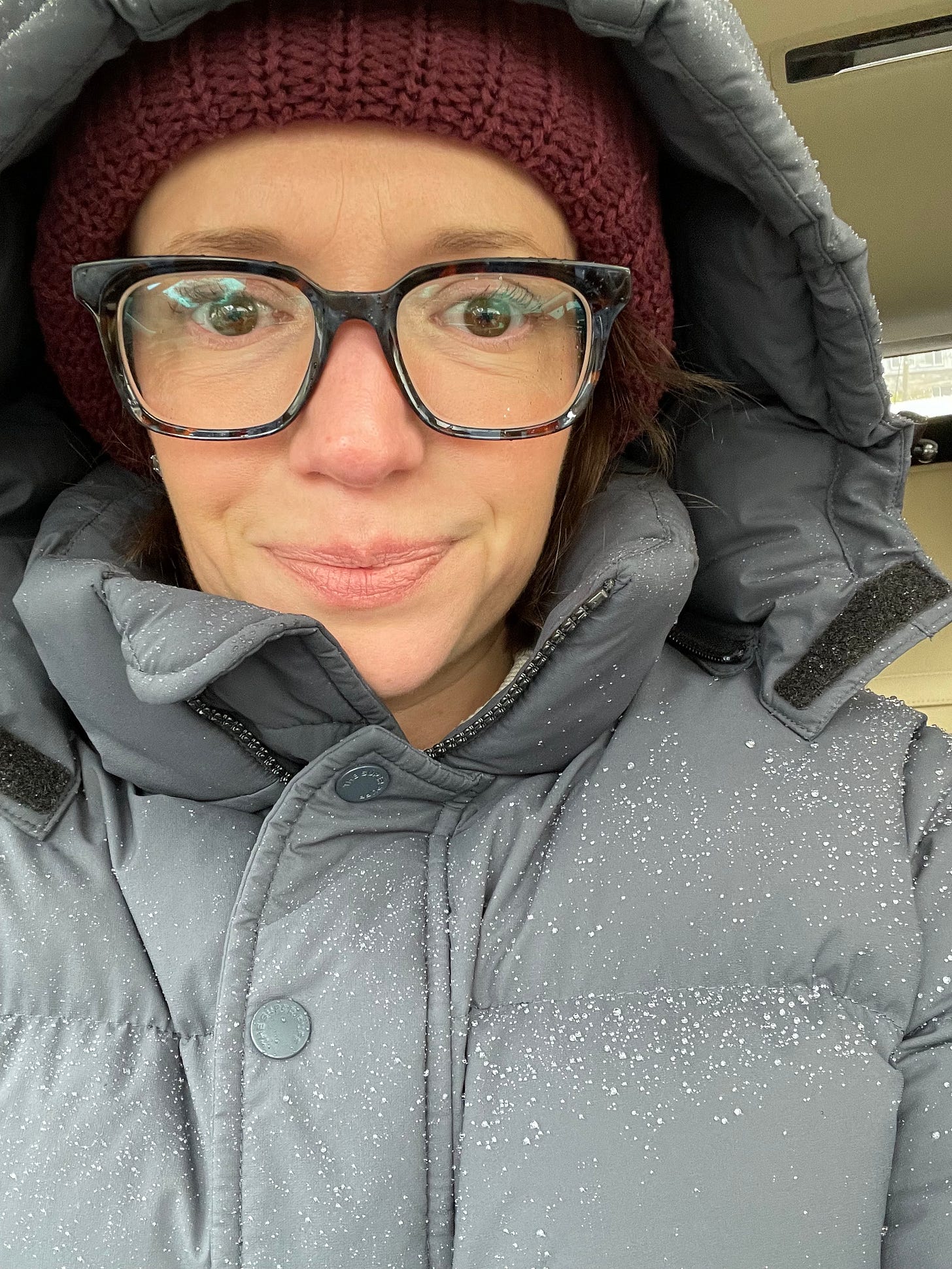 Jessica, a white woman in glasses, smiles with a lot of winter clothes on