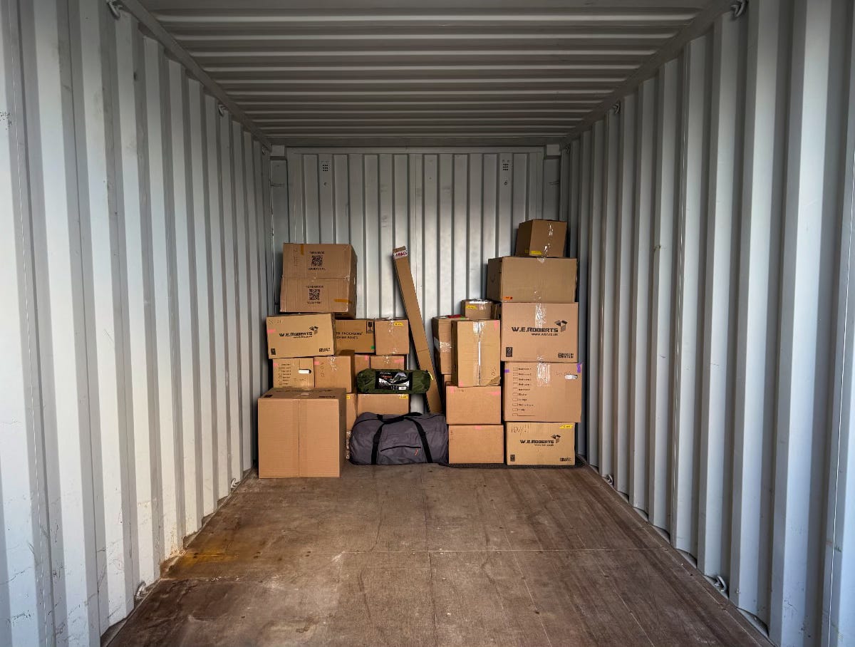A photo of a large shipping container with a few boxes in.