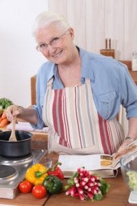 a smiling grandma stirring a pot in the kitchen a smiling grandma stirring a pot in the kitchen