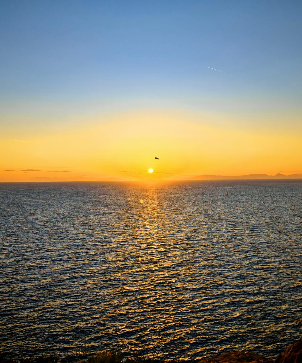 Golden-hour view of Cape Sounion’s rocky coastline and the Temple of Poseidon at sunset