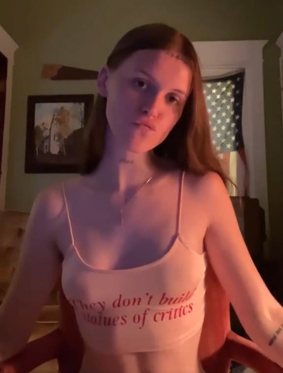 Ethel Cain vertical video still wearing They Don't Build Statues of Critics shirt