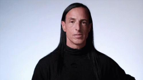 a man with long black hair is wearing a black shirt