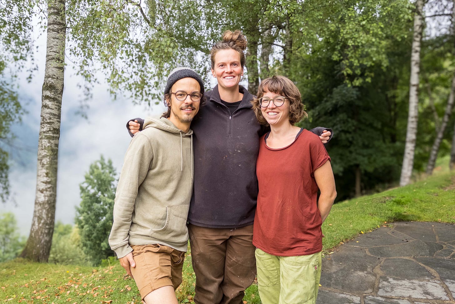 Das Kern-Team der Alpe Soladino steht Arm in Arm auf einer Wiese vor einem Wald. Von links: ???, Yasmin Spengler und Angelina Schwinger. Sie lächeln in die Kamera und tragen legere, praktische Kleidung für die Arbeit im Freien. Im Hintergrund sind Bäume und ein gepflasterter Weg zu sehen. Das Kern-Team der Alpe Soladino steht Arm in Arm auf einer Wiese vor einem Wald. Von links: ???, Yasmin Spengler und Angelina Schwinger. Sie lächeln in die Kamera und tragen legere, praktische Kleidung für die Arbeit im Freien. Im Hintergrund sind Bäume und ein gepflasterter Weg zu sehen.