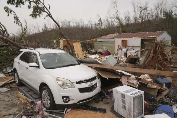 A vehicle sits in front of a damaged home and debris from a severe storm Saturday, March 15, 2025, in Wayne County, Mo. (AP Photo/Jeff Roberson)