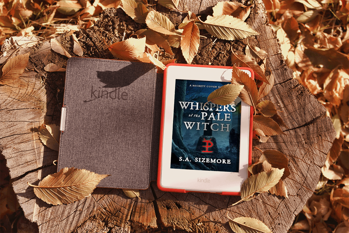 Book "Whispers of a Pale Witch" on a Kindle that is sitting on a tree stump surrounded by autumn leaves Book "Whispers of a Pale Witch" on a Kindle that is sitting on a tree stump surrounded by autumn leaves