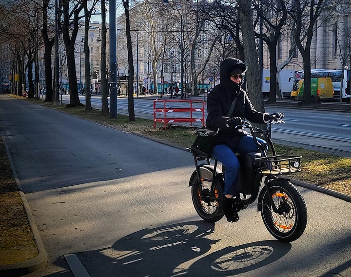 Two photos of transit in Vienna. First photo: A woman rides a fat-tire ebike along a bike path. Second photo: A red and gray streetcar along Vienna's ring street.