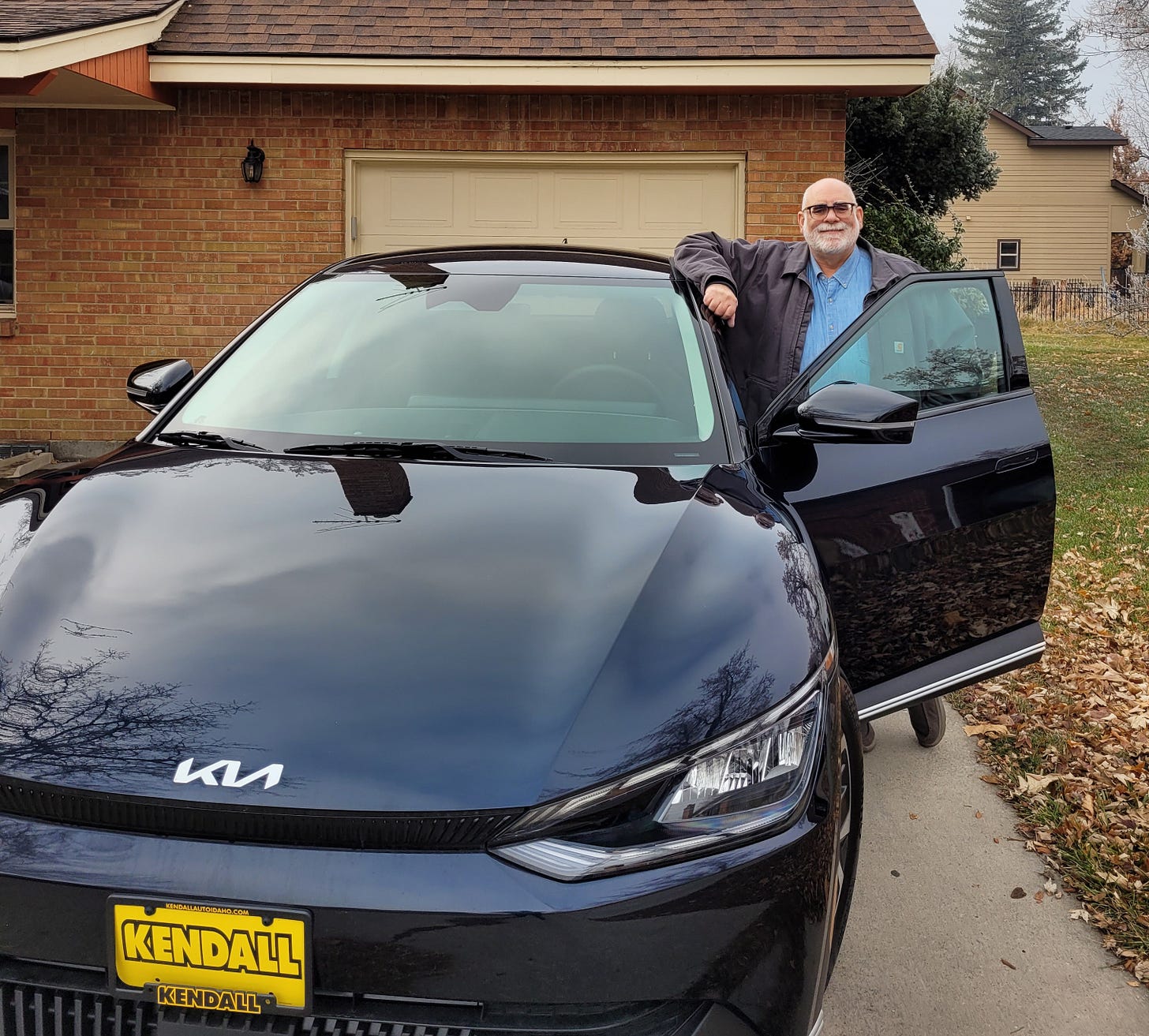 Doktor Zoom poses with his new Kia EV6, which really is a sparkly dark blue when it's sunny out. 