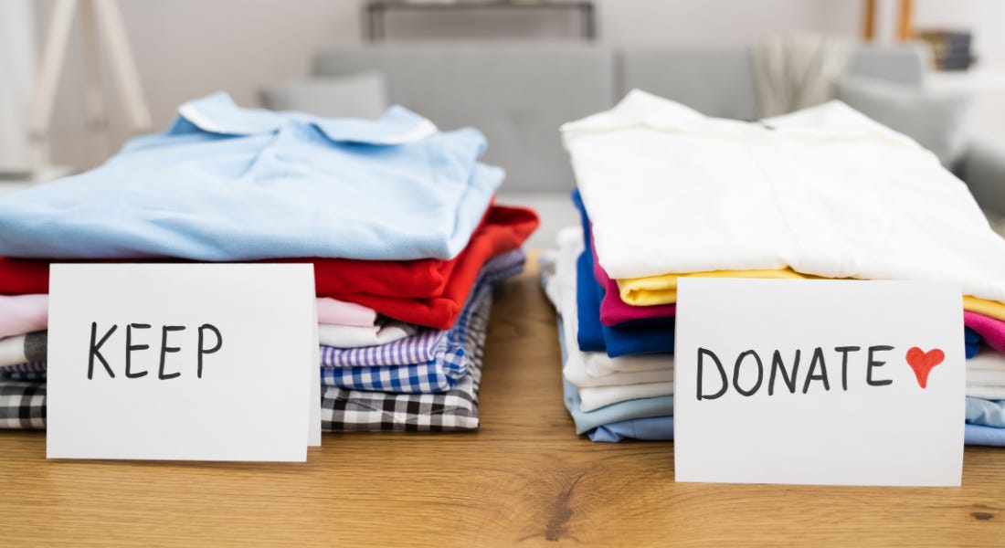 A table with two piles of folded clothes with 'keep' and 'donate' signs next to them A table with two piles of folded clothes with 'keep' and 'donate' signs next to them