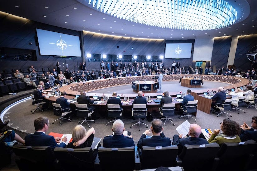 A group of people sit around a circular table in a large room