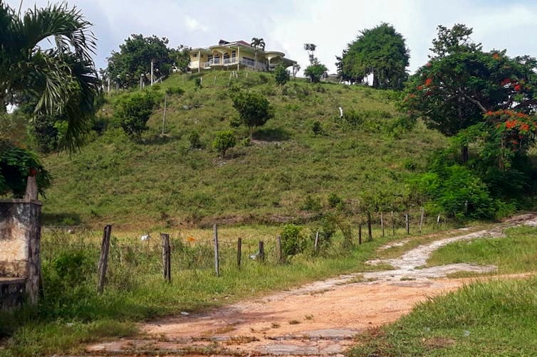 A house is seen on the top of a grassy hill. A house is seen on the top of a grassy hill.