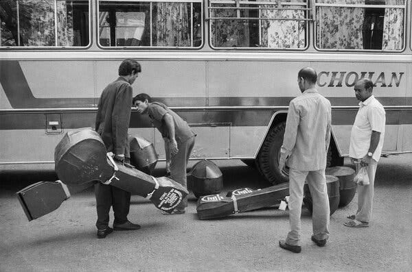 Men load Indian classical instruments, in cases, onto a 40-seater bus.