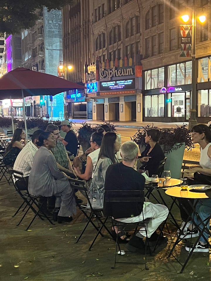 first image is an ice bucket full of wine bottles, second image is a group of people sitting outside a cafe at night drinking wine on the sidewalk.