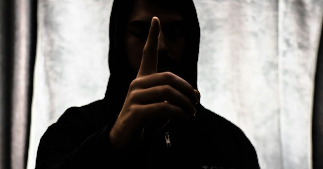person in black hoodie showing middle finger person in black hoodie showing middle finger