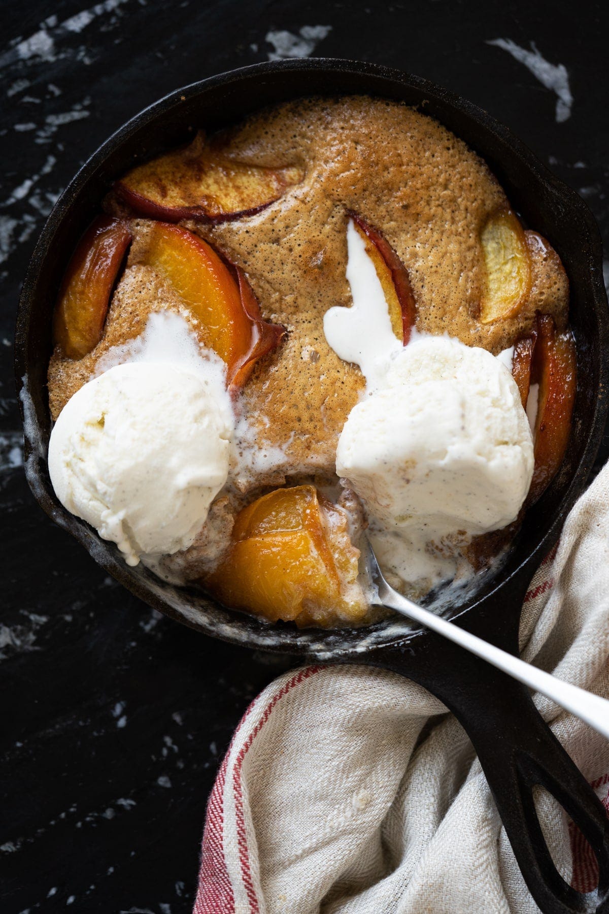 Keto peach cobbler with a flourless cake like topping and vanilla ice cream