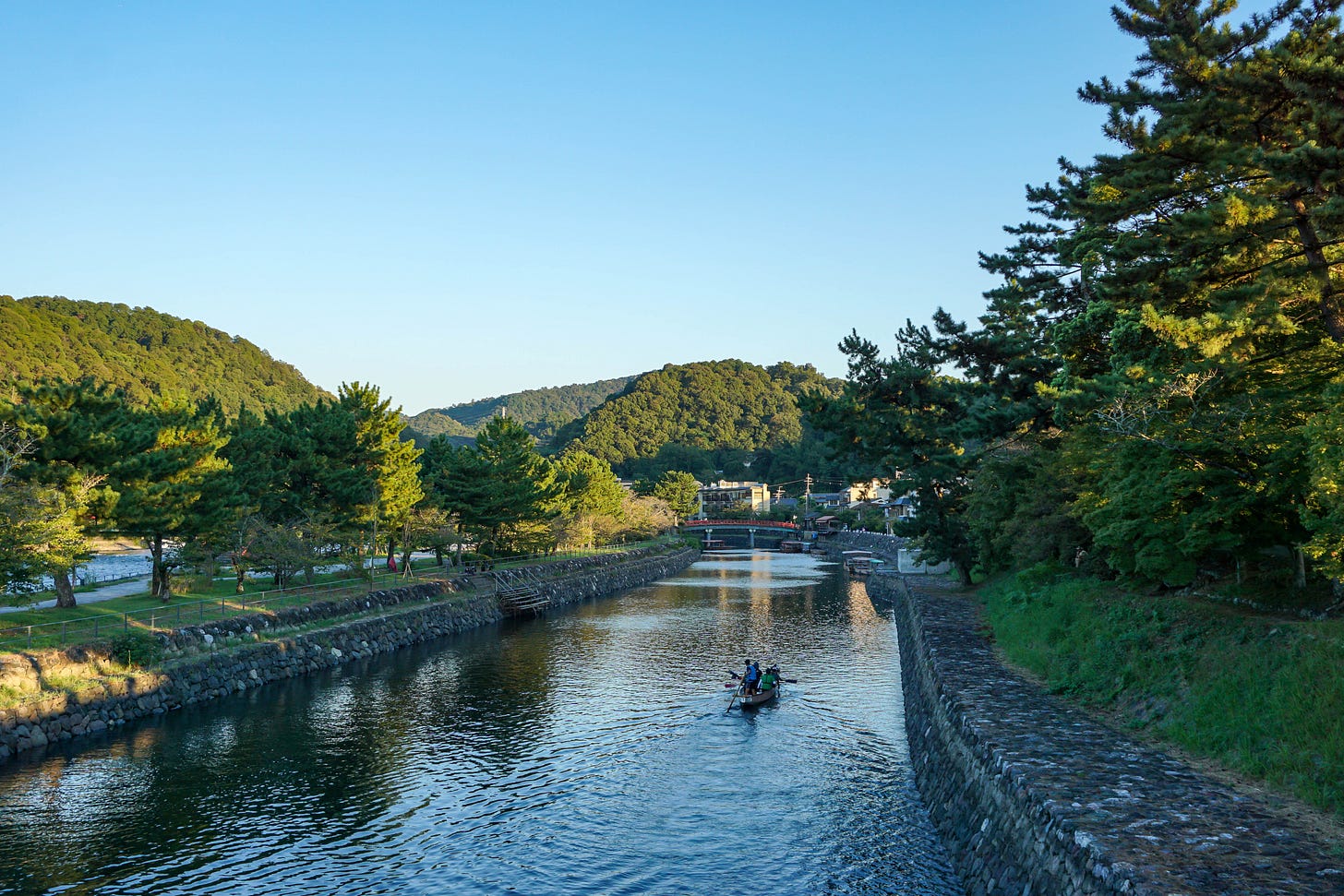 View of the Uji River from a bridge across it, with afternoon sunlight and a boat in the water View of the Uji River from a bridge across it, with afternoon sunlight and a boat in the water