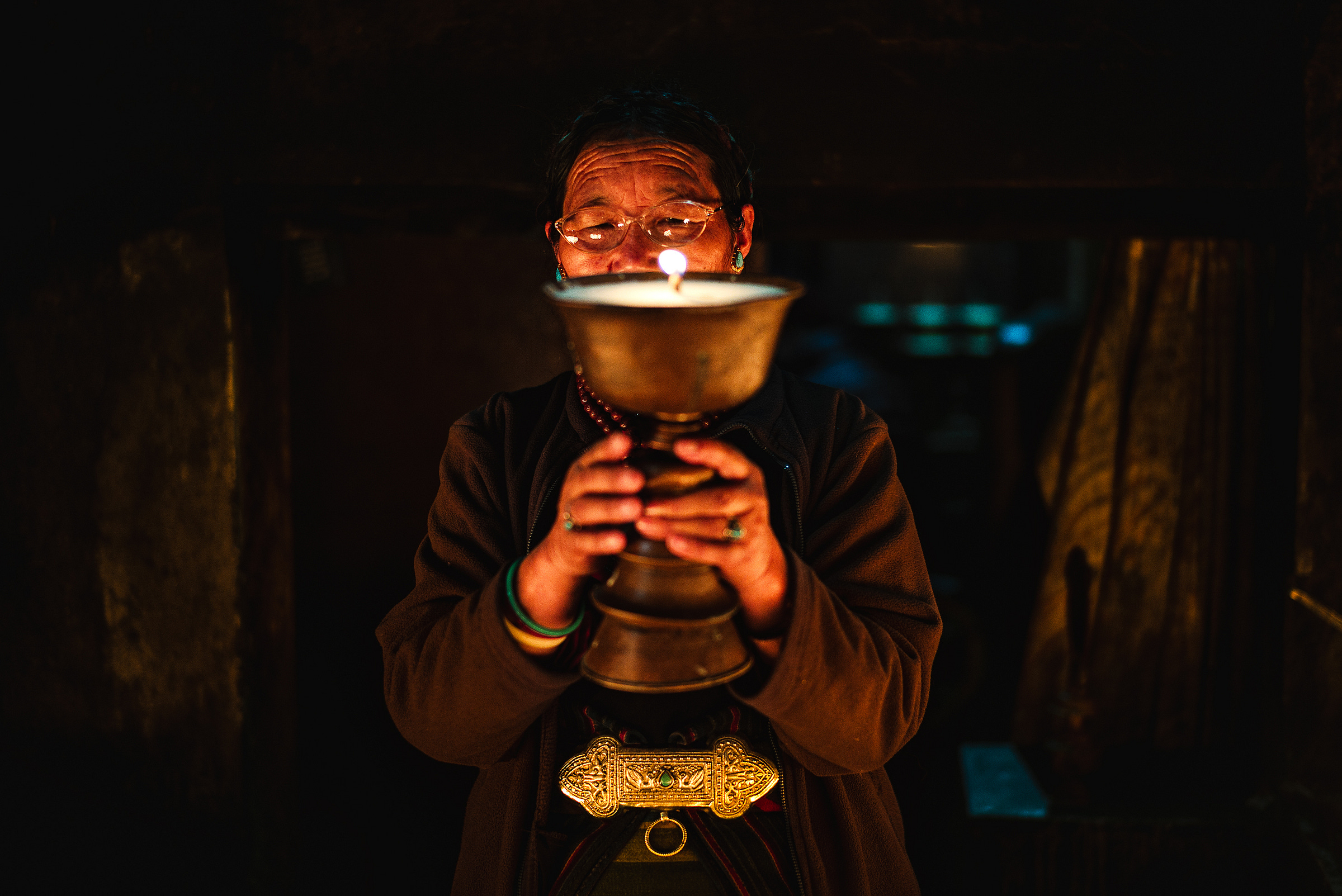 A woman lights a yak butter lamp in the temple. A woman lights a yak butter lamp in the temple.