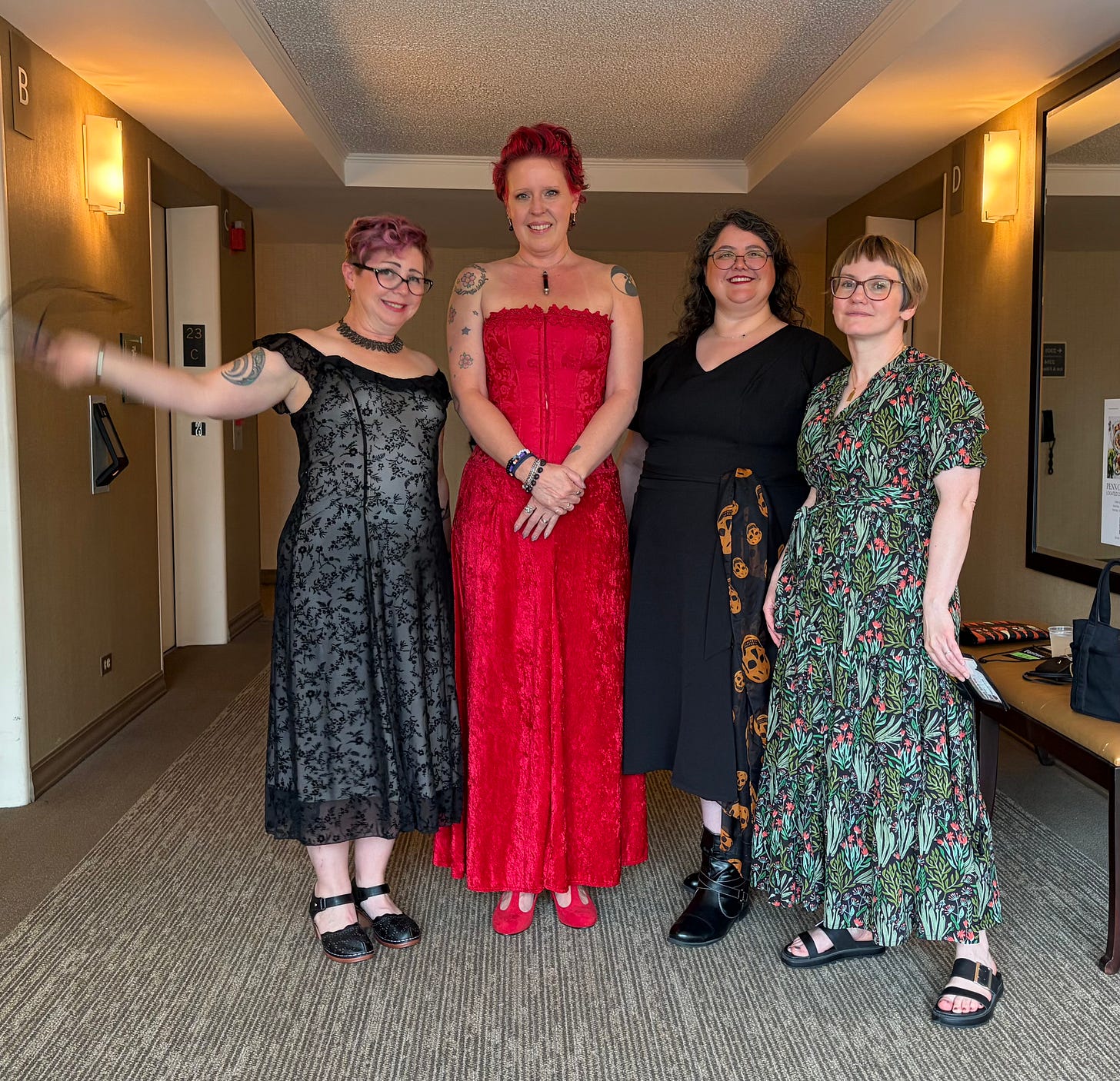 Four women in dresses standing in a hallway