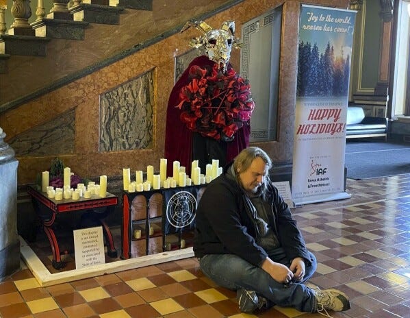FILE - A man prays in Latin in front of a display installed by Satanic Temple Iowa at the Iowa State Capitol in Des Moines, Iowa, on Tuesday, Dec. 12, 2023. A Mississippi man accused of destroying a statue of the pagan idol Baphomet at Iowa's state Capitol pleaded guilty Friday to a reduced charge in return for prosecutors dropping a felony hate crime count. (Caleb McCullough/The Gazette via AP, file) FILE - A man prays in Latin in front of a display installed by Satanic Temple Iowa at the Iowa State Capitol in Des Moines, Iowa, on Tuesday, Dec. 12, 2023. A Mississippi man accused of destroying a statue of the pagan idol Baphomet at Iowa's state Capitol pleaded guilty Friday to a reduced charge in return for prosecutors dropping a felony hate crime count. (Caleb McCullough/The Gazette via AP, file)
