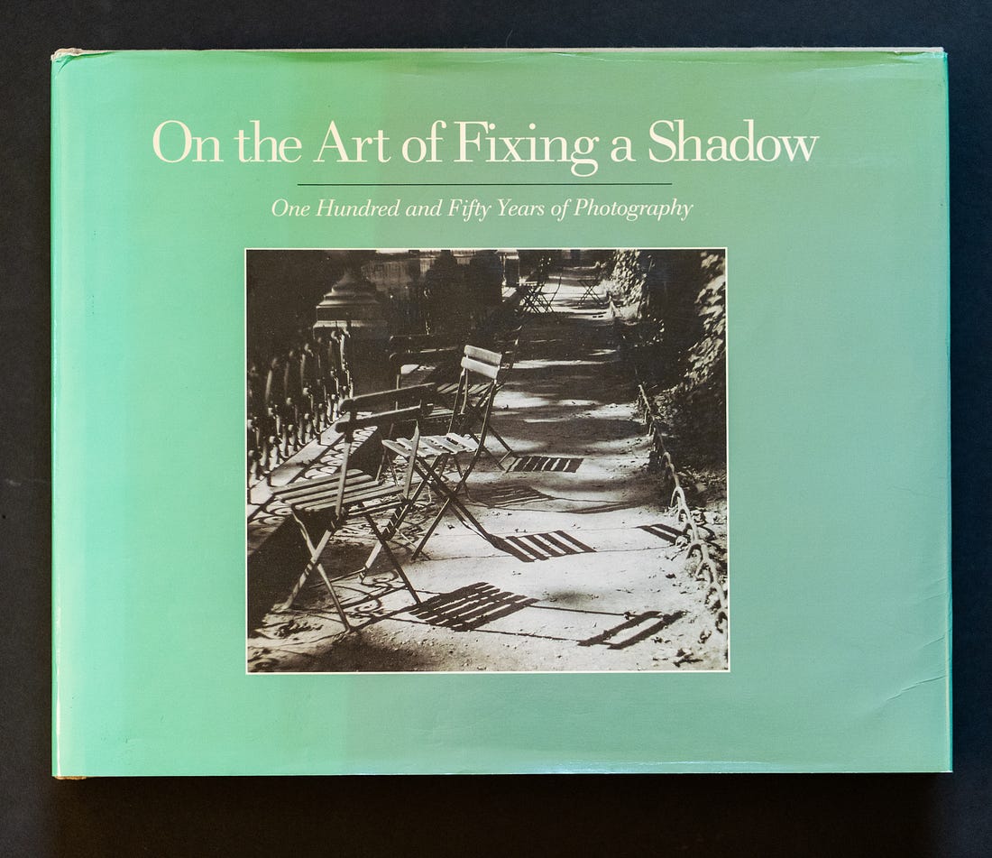 A photo of the book On the Art of Fixing a Shadow, which has a pale green cover and a black and white photo of chairs