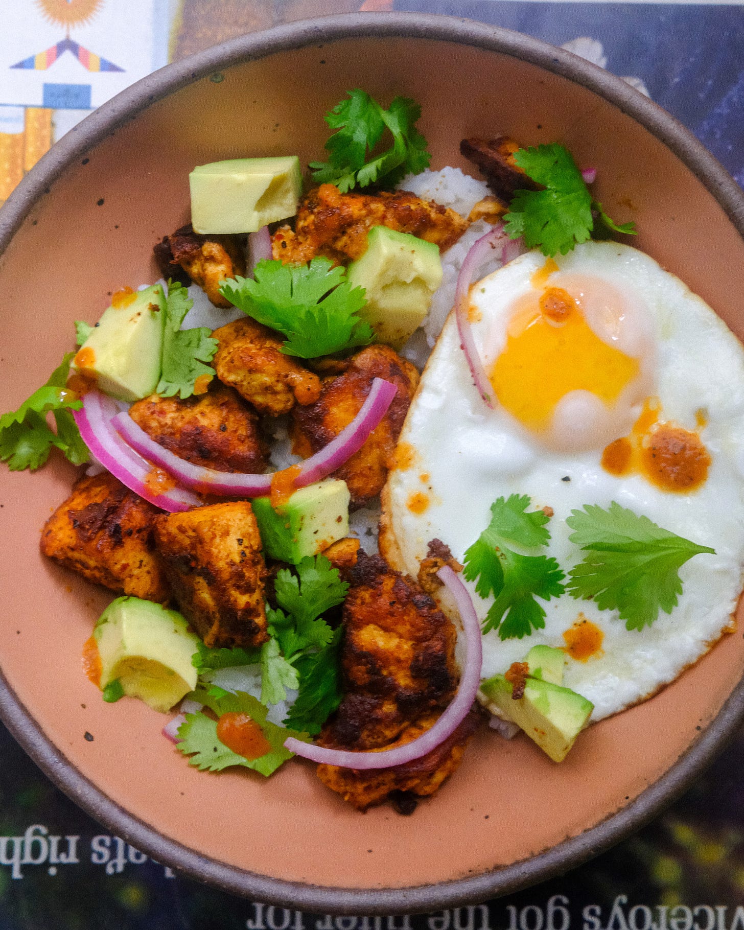 Tofu rice bowl with egg, cilantro, red onion, and avocado.