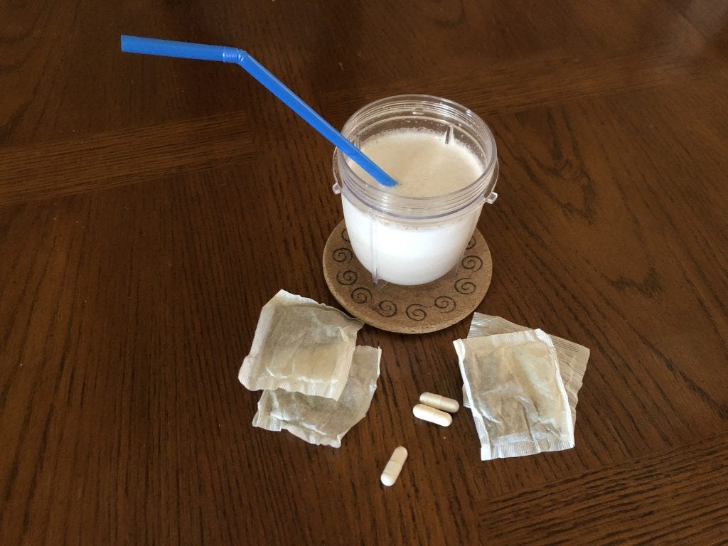 A smoothie in a cup with a blue straw on a brown wooden table with nearby tea packets and scattered capsules as examples of ways magic mushrooms might be taken for psychedelic parenting A smoothie in a cup with a blue straw on a brown wooden table with nearby tea packets and scattered capsules as examples of ways magic mushrooms might be taken for psychedelic parenting