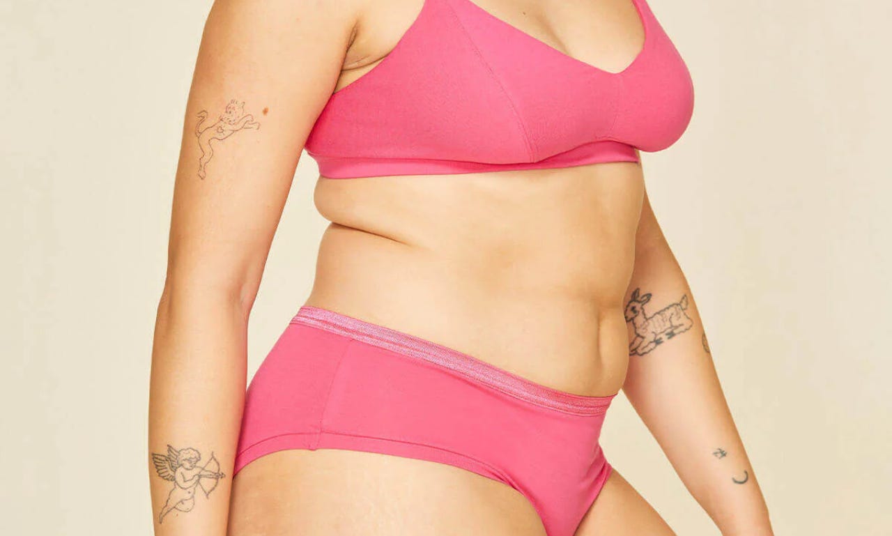 a model with tattoos models a matching pink bra and panties set.