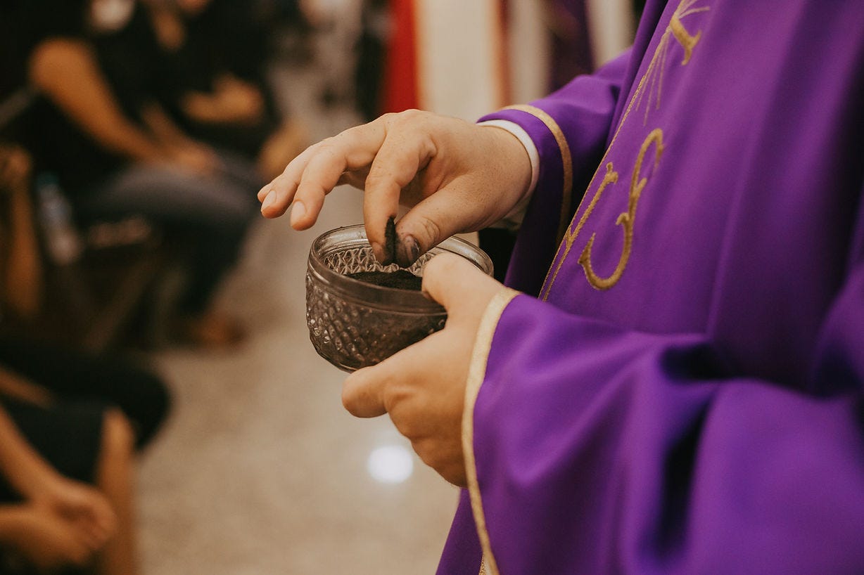 Priest in purple vestments distributing ashes