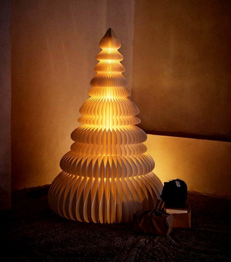 White decorative Christmas tree with internal light, 3D design, placed on the floor.