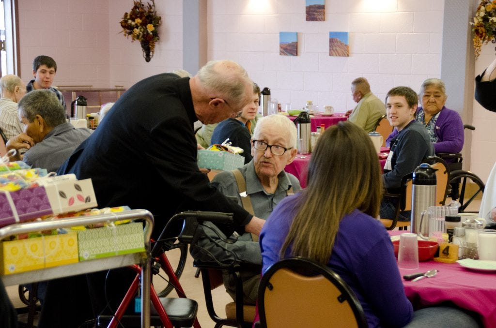 Fr. James Walker, pastor of St. John Vianney church in Gallup, hands out gifts to residents in celebration of the feast of St. Joseph.