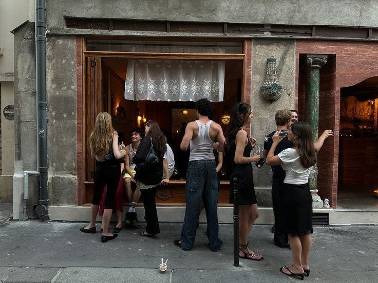This may contain: a group of people standing in front of a building with wine glasses on the windows