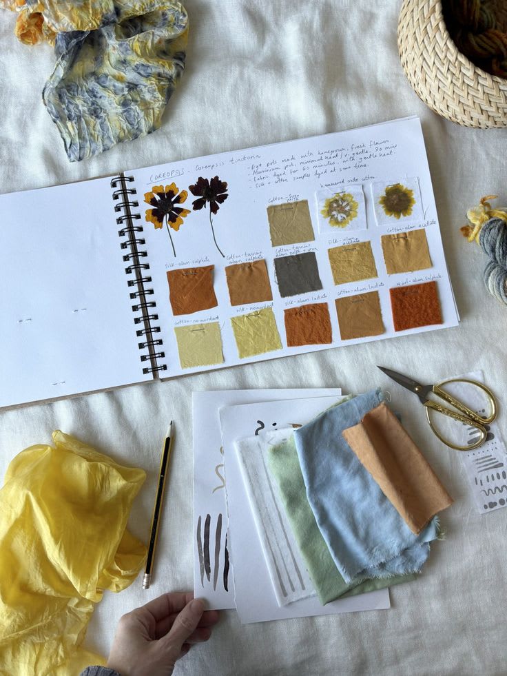 This may contain: someone is working on their art project with color swatches, scissors and other crafting supplies